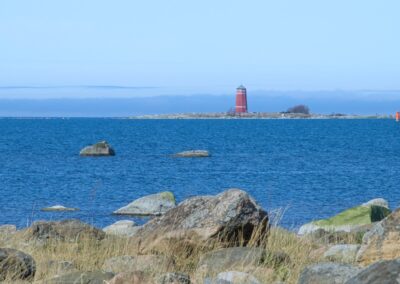 a red light house sitting in the middle of a body of water
